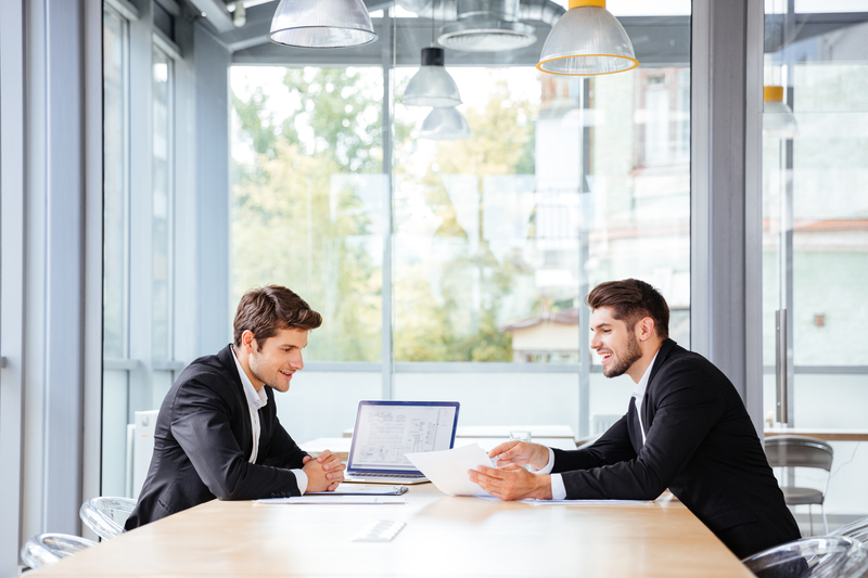 Acountant and happy businessman working together using laptop on business meeting